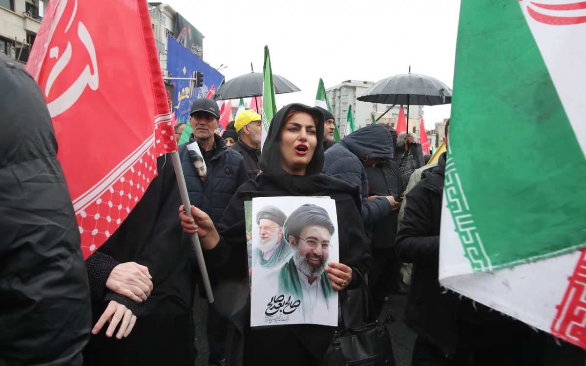 Người dân Iran cầm chân dung cha con tân Lãnh đạo Iran Mojtaba Khamenei. Ảnh: AP.