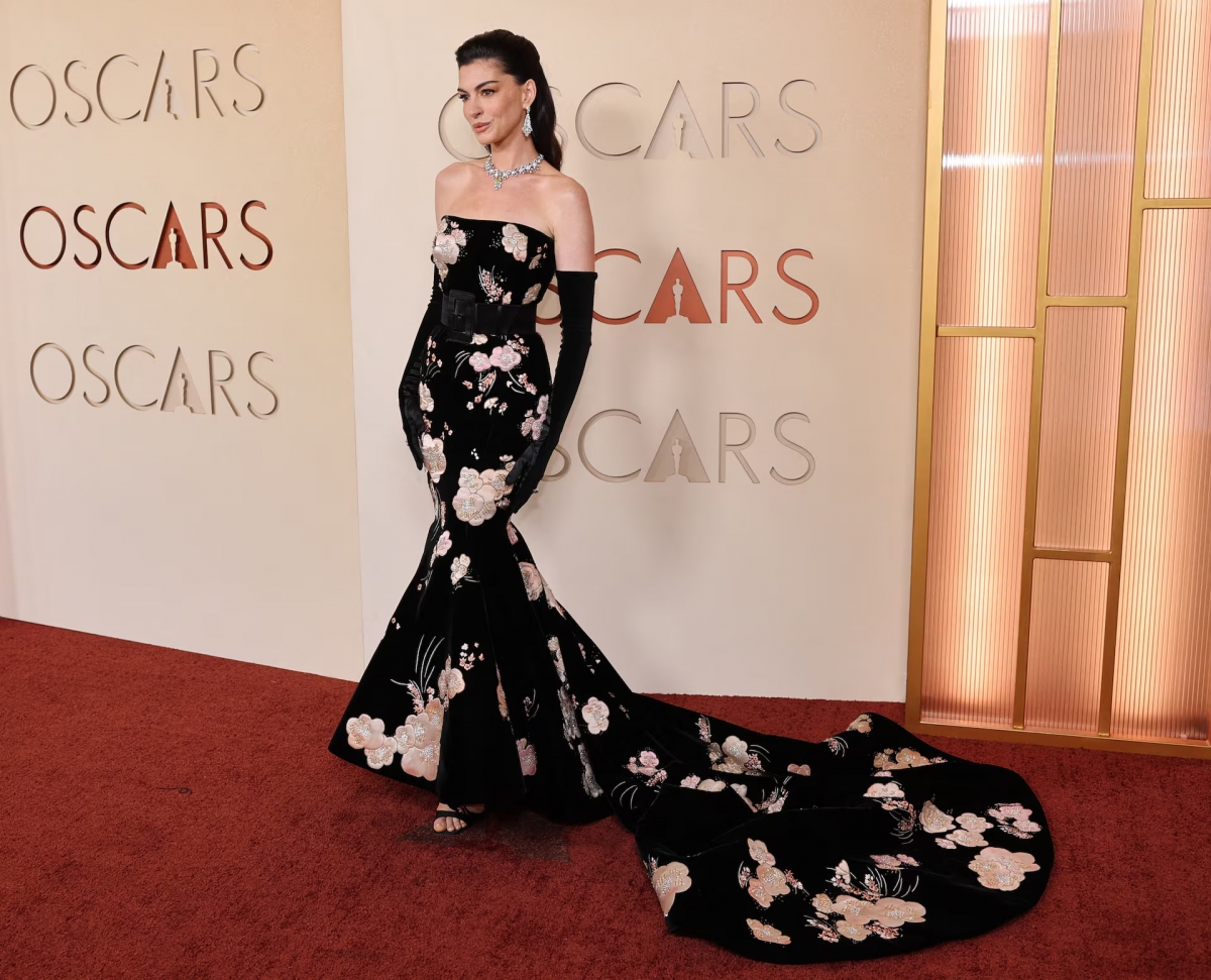 Trong khi đó, Anne Hathaway diện chiếc váy đen đuôi cá không dây vai của Valentino, được điểm xuyết bằng những bông hoa màu hồng nhạt. Thiết kế được đánh giá là khá đẹp và tôn dáng, song các phụ kiện đi kèm lại không làm nổi bật trang phục. Nữ diễn viên kết hợp váy với thắt lưng đen và găng tay dài đến khuỷu tay, khiến tổng thể trở nên nặng nề hơn so với vẻ mềm mại của chiếc váy hoa.