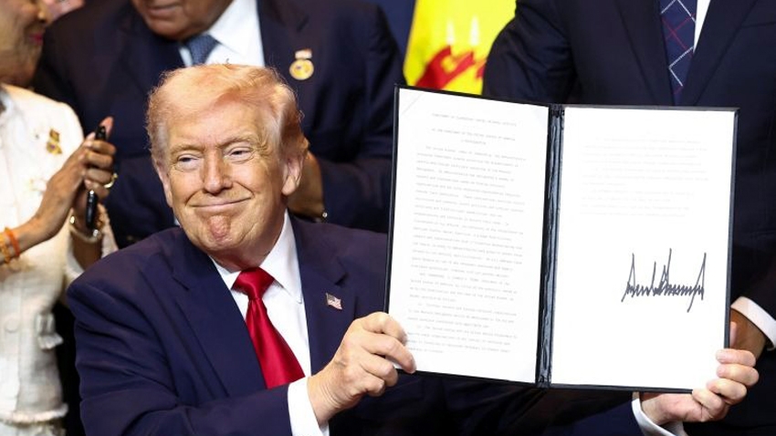 Tổng thống Mỹ Donald Trump giơ cao bản cam kết đã ký về việc chống lại hoạt động tội phạm của các băng đảng ma túy tại Doral, Florida - Ảnh: Reuters