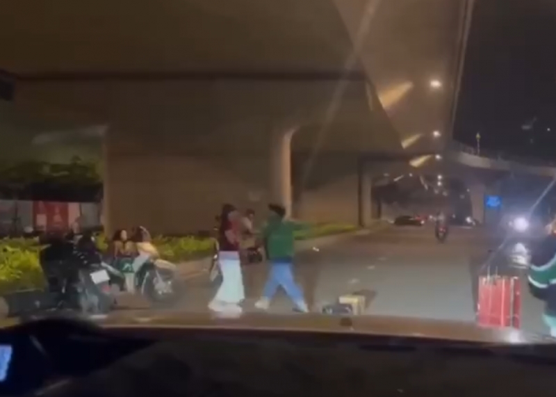 Hình ảnh camera trên xe ô tô của một người dân ghi lại cảnh người đàn ông mặc đồng phục xe ôm công nghệ đuổi đánh một người phụ nữ (ảnh cắt từ clip).