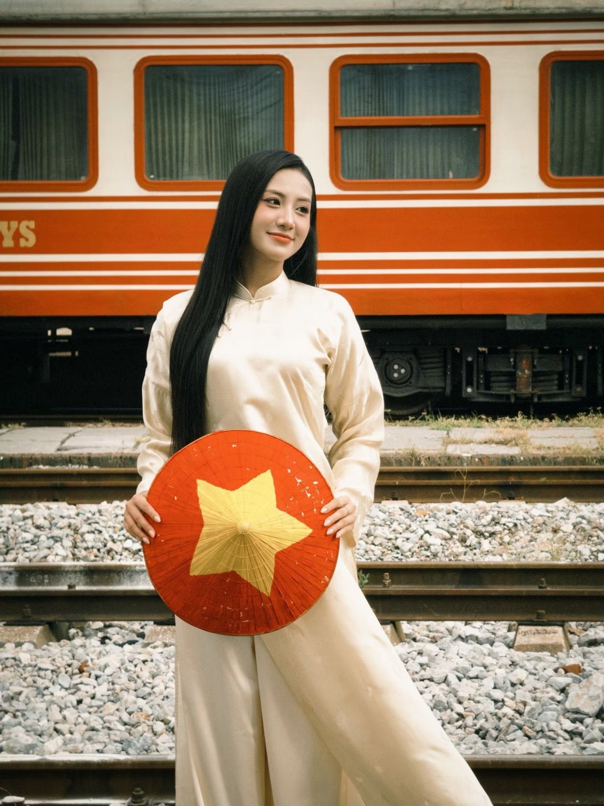 Hoa hậu Hà Trúc Linh diện áo dài phom dáng truyền thống, cùng nón lá in họa tiết cờ đỏ sao vàng.