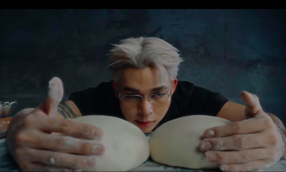 Một số cảnh trong MV, ca sĩ làm những động tác như nhào, cán bột, tẩm ướp nguyên liệu, vấp phải nhiều ý kiến trái chiều từ khán giả (Ảnh trong MV)