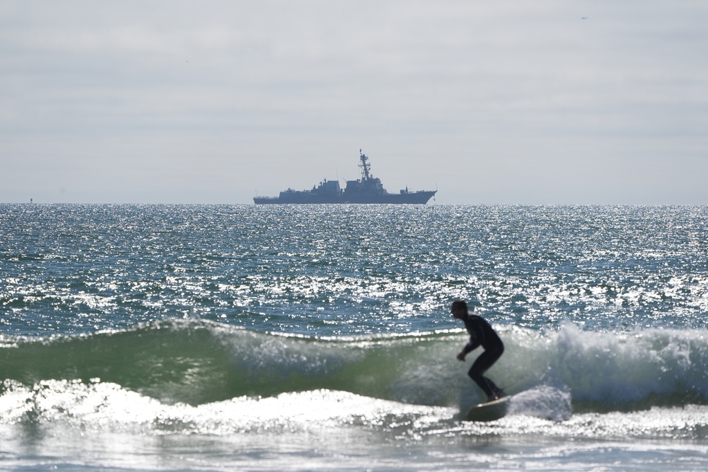 Một người đàn ông lướt sóng gần một bữa tiệc bên bờ biển để chào mừng sự trở lại của tàu Artemis II.