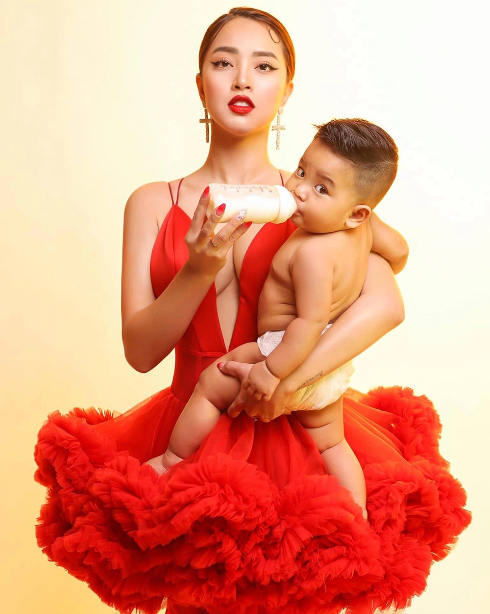 Hải Băng diện đầm xẻ ngực sâu, bế con trai cưng trong bộ ảnh mới. Sau hai tháng sinh quý tử thứ ba cho chồng, cô nhanh chóng lấy lại vóc dáng. Nhóc tì nhà Hải Băng - Thành Đạt được nhận xét có gương mặt giống hệt bố.