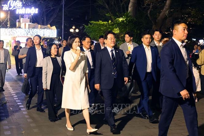 Tổng thống Hàn Quốc Lee Jae Myung và Phu nhân Kim Hae Kyung vừa ăn kem Thuỷ Tạ vừa đi dạo quanh hồ Hoàn Kiếm. Ảnh: Phạm Kiên/TTXVN