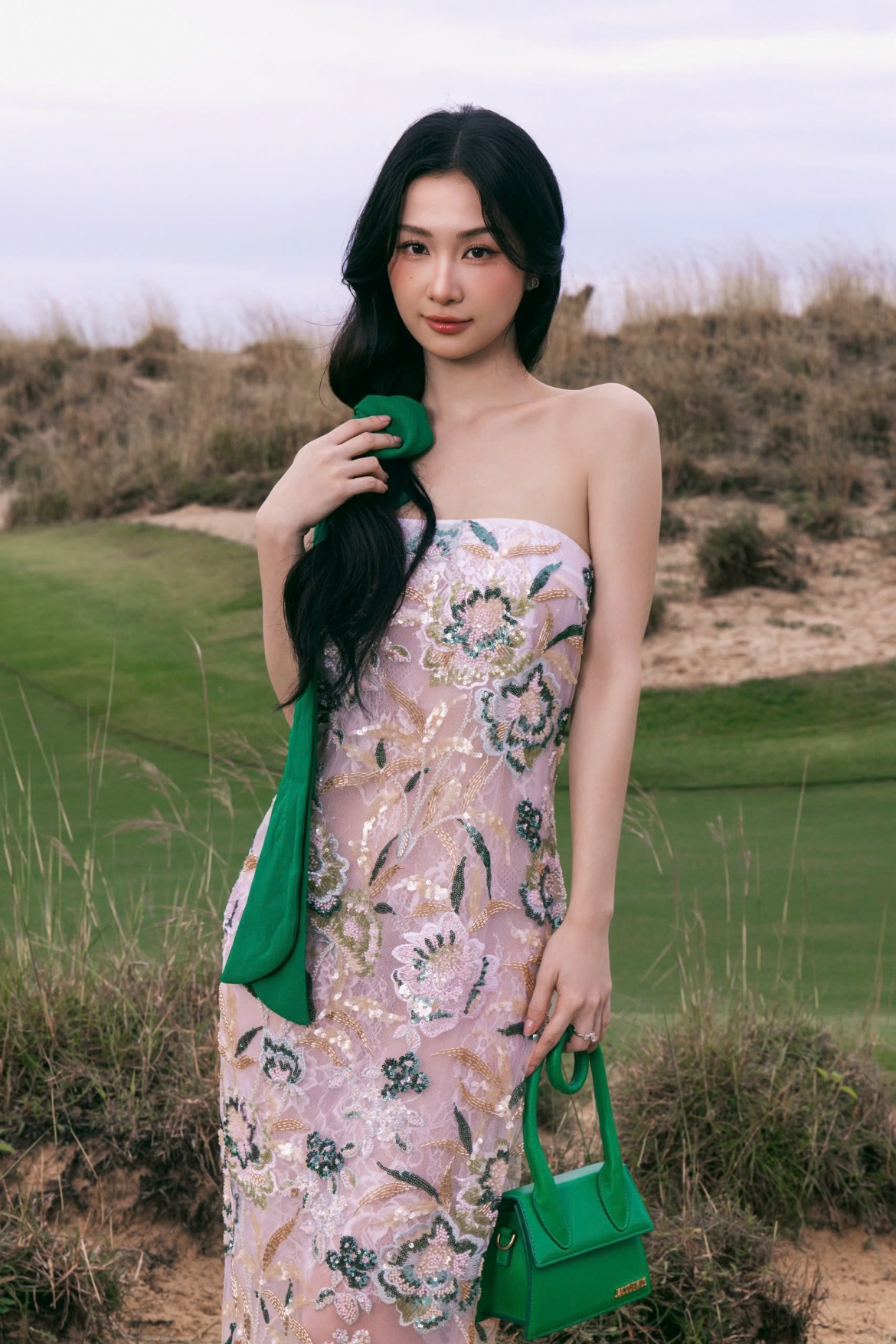 Jun Vũ diện đầm cúp ngực đính sequin dáng dài, kết hợp cùng túi Jacquemus và nơ buộc tóc cùng tone màu.