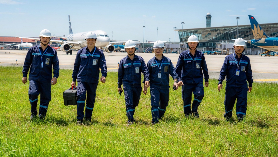 Giữa không gian rộng lớn phủ kín bê tông hấp thụ nhiệt, khu bay Nội Bài những ngày này chẳng khác nào một “chảo lửa” khổng lồ. Nhiệt nóng hầm hập từ mặt sân cộng thêm hơi nóng tỏa ra từ động cơ tàu bay khiến không khí trở nên ngột ngạt, bỏng rát.