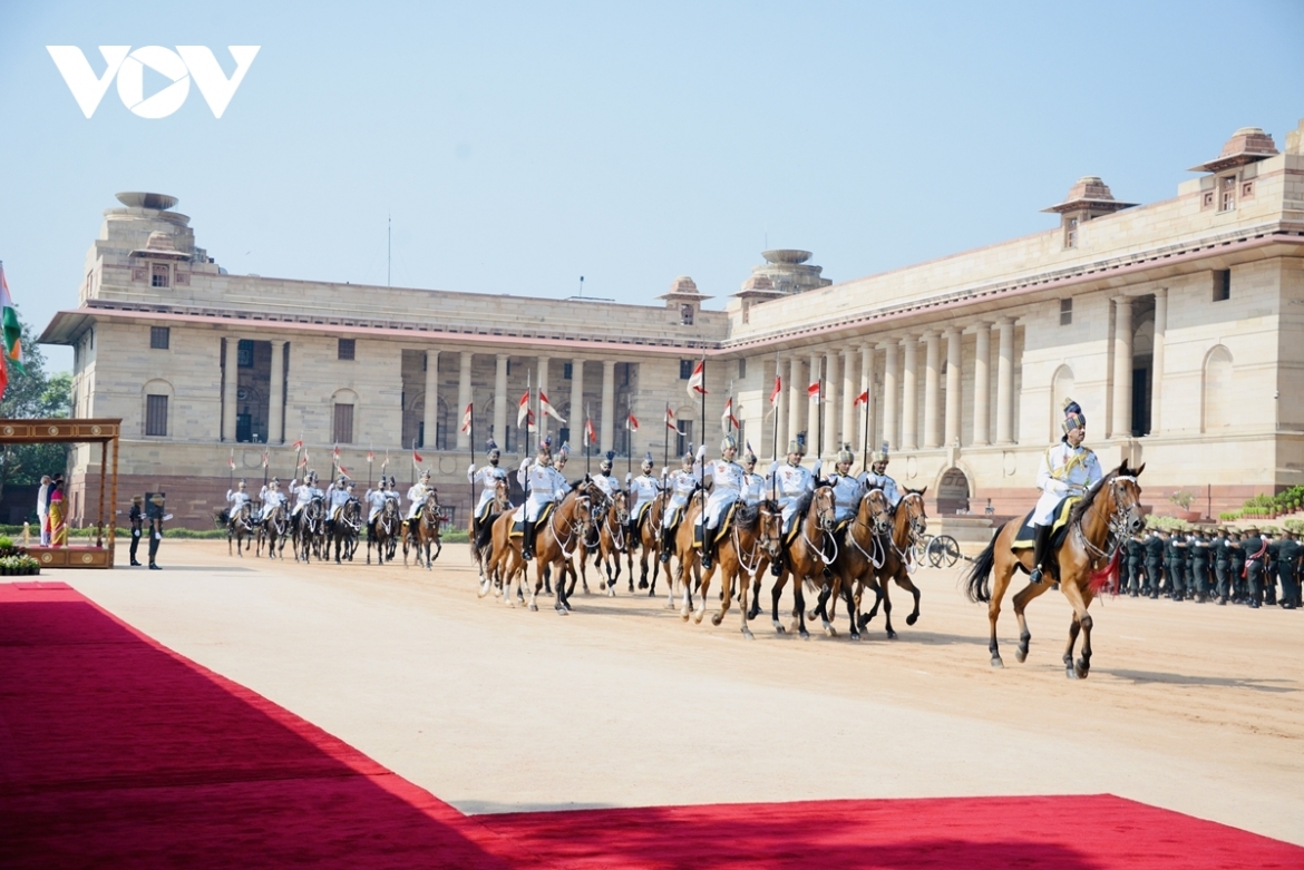 Tổng thống Droupadi Murmu, Thủ tướng Ấn Độ Narendra Modi trân trọng mời Tổng Bí thư, Chủ tịch nước Tô Lâm bước lên bục danh dự, dưới Quốc kỳ Việt Nam và Ấn Độ, cùng với 21 loạt đại bác chào mừng, quốc thiều hai nước Việt Nam - Ấn Độ được đội Quân nhạc cử lên trang trọng.