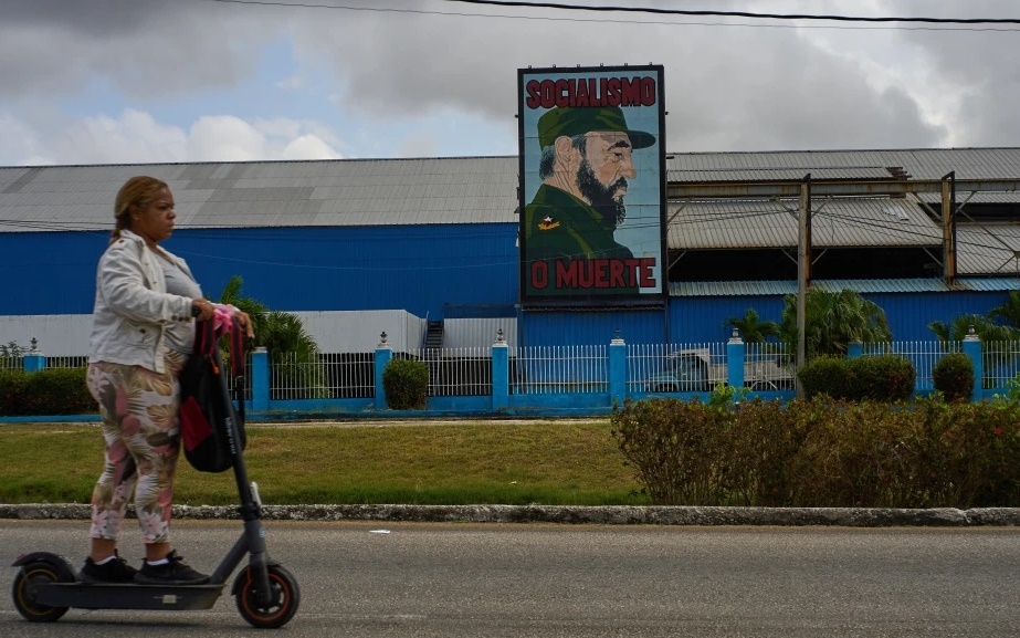 Một phụ nữ đi xe scooter điện trên con đường ở Cuba. Ảnh: AP.