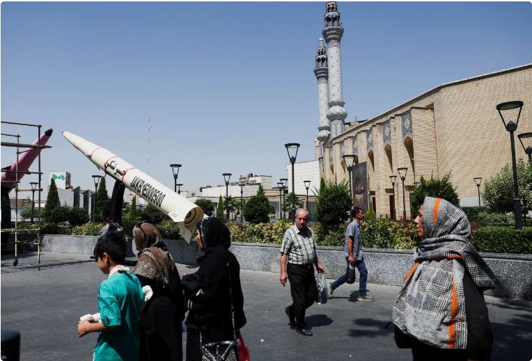 Người dân Iran đi qua khu vực đặt mô hình tên lửa của Iran. Ảnh: Reuters