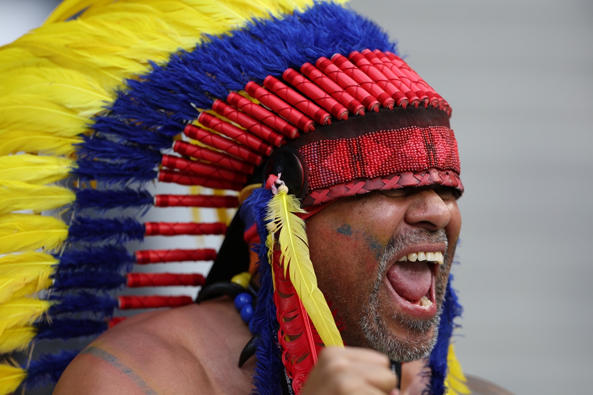 Một cổ động viên Colombia đội mũ lông vũ nhiều màu sắc hò hét trước khi trận đấu giữa Uzbekistan và Colombia bắt đầu.
