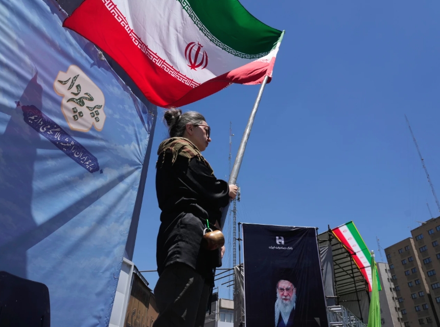 Một người phụ nữ cầm quốc kỳ Iran trên đường phố. Ảnh: AP