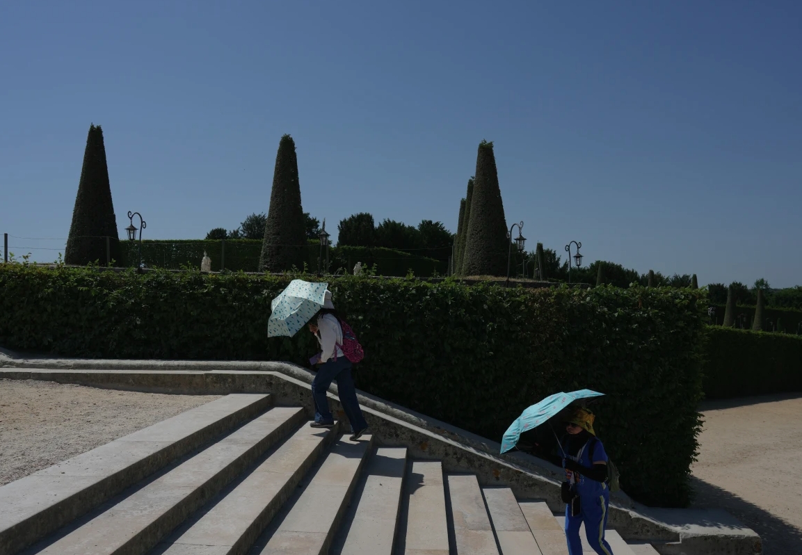 Du khách dùng ô che nắng khi đi dạo trong khu vườn của Cung điện Versailles, ngoại ô Paris, trong đợt nắng nóng với nhiệt độ lên tới trên 40 độ C ngày 22/6. 