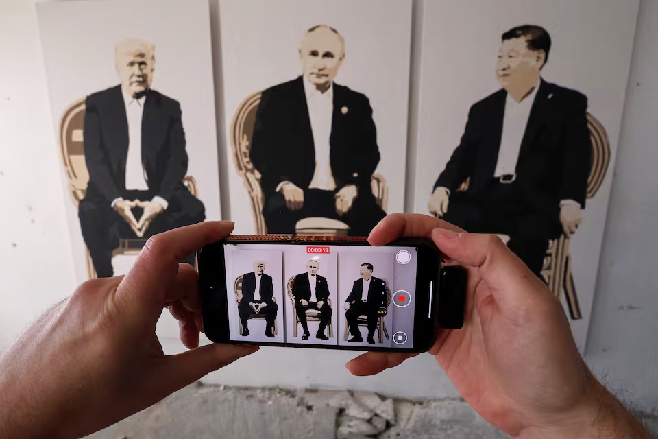 Khách tham quan ghi hình tác phẩm nghệ thuật mô tả Tổng thống Mỹ Donald Trump, Tổng thống Nga Vladimir Putin và Chủ tịch Trung Quốc Tập Cận Bình tại một triển lãm ở Yalta, Crimea ngày 8/2/2025. Ảnh: Reuters