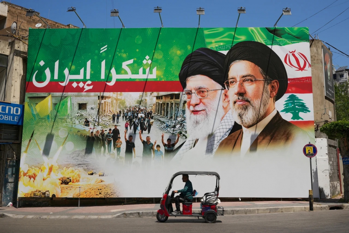 Một người đàn ông lái xe ba bánh chạy qua tấm biển có hình cố Lãnh tụ tối cao Iran Ali Khamenei và con trai ông, tân Lãnh tụ tối cao Mojtaba Khamenei, tại khu Dahiyeh, phía Nam thủ đô Beirut, Lebanon, ngày 15/6/2026. Ảnh: AP