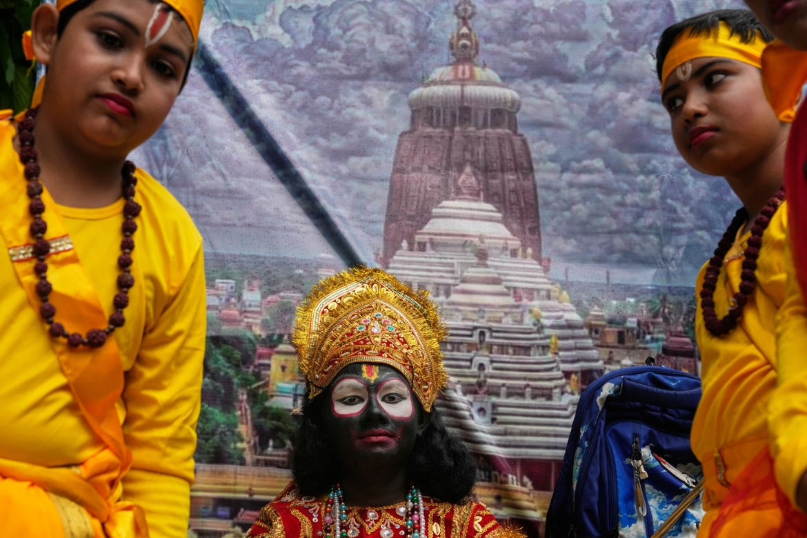 Một đứa trẻ (ở giữa) mặc trang phục thần Hindu Jagannath đi trên một cỗ xe rước trong lễ hội Rath Yatra tại Kolkata.