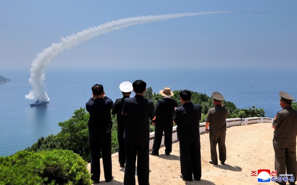 Lãnh tụ Triều Tiên Kim Jong Un cùng các quan chức Triều Tiên từ trên bờ biển thị sát cuộc thử vũ khí của chiến hạm. Ảnh: KCNA.