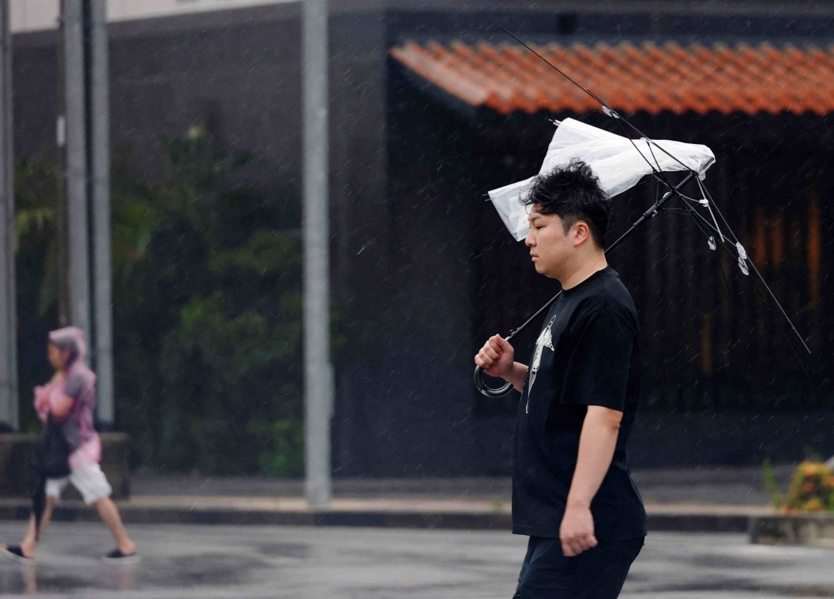 Gió lớn do bão lật ngược ô của một người đi đường tại Ishigaki.