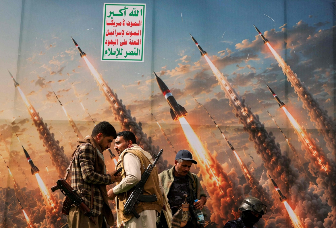 Các thành viên của lực lượng Houthi đứng trước một tấm biểu ngữ tại thủ đô Sanaa, Yemen (Ảnh: Reuters)